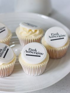 four cupcakes on a plate with labels for pink aubergine and milk