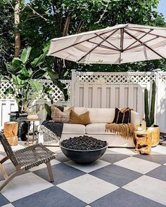 an outdoor living area with checkered tile flooring and white umbrella over the couch