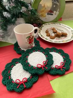 three crocheted coasters on a table next to a coffee cup and plate