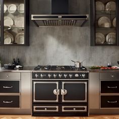 a stove top oven sitting inside of a kitchen next to a counter with plates on it