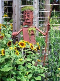 a garden with sunflowers and a scarecrow in the center, surrounded by plants