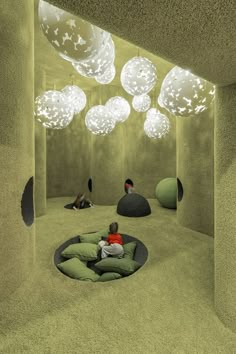 a child is sitting on a bean bag in the middle of a room with lights hanging from the ceiling