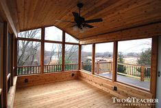 an empty room with wood flooring and ceiling fan in the center, looking out onto a wooded area