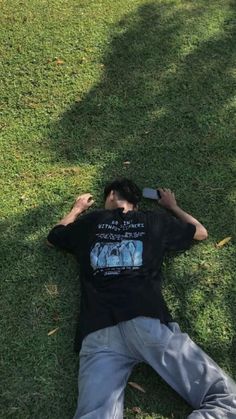 a man laying in the grass with his cell phone