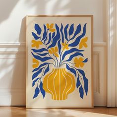 a yellow and blue vase with flowers in it on the floor next to a wall