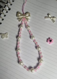 a pink and white beaded necklace next to other beads on lined paper with crochet hooks