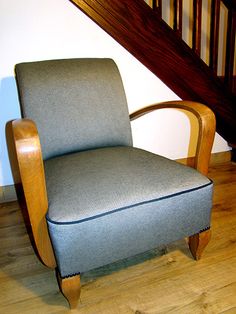 a chair sitting in the middle of a room next to a stair case and wooden handrail