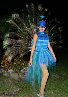 a woman wearing a blue and green costume with peacock feathers on it's head