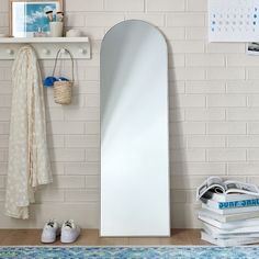 a white mirror sitting on top of a shelf next to a pile of books and shoes