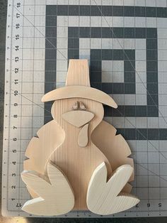 a wooden cutout of a turkey with a hat on it's head sitting next to a ruler