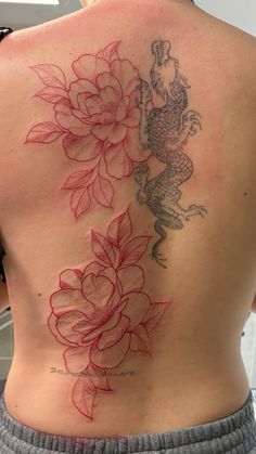 the back of a woman's body with flowers and a rooster tattoo on it