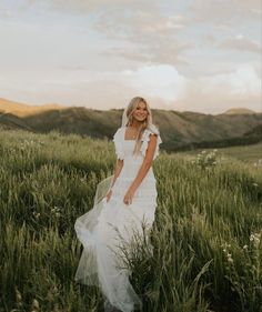 a woman in a white dress standing in tall grass