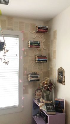 a room that has some books on the wall and a vase with flowers in it