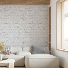 a living room with a white couch and table in front of a brick wall that has been painted white