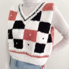 a woman is wearing a sweater with black, white and red squares on the front