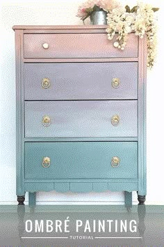 an ombre painted dresser with flowers on top