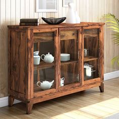 a wooden cabinet with glass doors and shelves on the top, in front of a wall