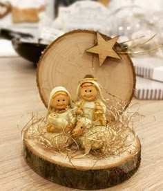 two small figurines sitting on top of a piece of wood next to a star