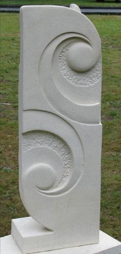 a large white sculpture sitting on top of a cement block in the middle of a field