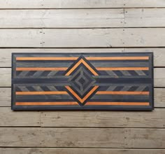 a wooden wall hanging with an orange and black design on the wood planks next to it