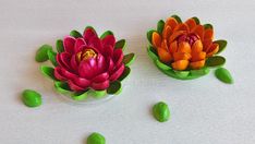 two small plastic flowers sitting on top of a white table next to green beans and peas