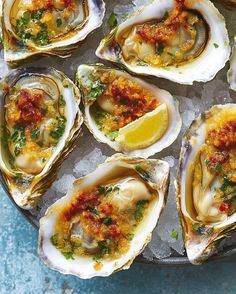 several oysters are on an ice tray with lemon wedges and garnishes