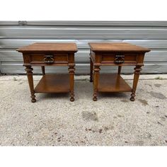 two wooden end tables sitting next to each other on top of a cement floor in front of a garage door