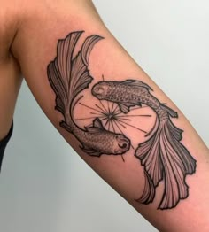 a black and white tattoo of two fish on the arm