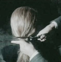 a woman is cutting her hair with scissors