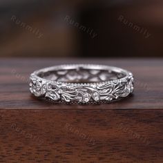 an ornate wedding ring with filigrees and scrolls on the sides, sitting on a wooden surface