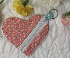 a pink heart shaped purse with flowers on the side and a zippered keychain attached to it