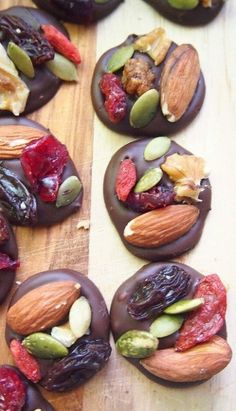 chocolate covered cookies decorated with nuts and dried fruit on a cutting board, ready to be eaten