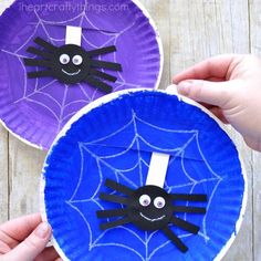 two paper plates decorated to look like bats and spider webs with hands holding them