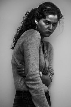 black and white photograph of a woman leaning against a wall with her hands on her hips