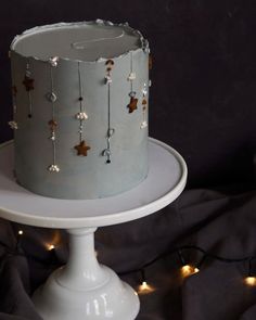 a frosted cake sitting on top of a white cake plate with lights around it