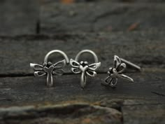 two small silver earrings sitting on top of a wooden table