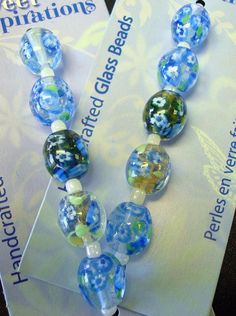 two blue and green glass bead necklaces on top of a white piece of paper