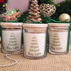 three candles are sitting on a table with christmas decorations in front of them and one candle has writing on it