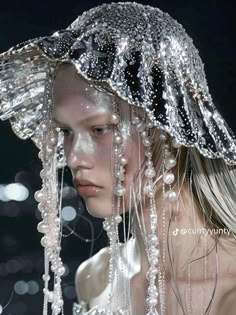 a woman with long hair wearing a hat covered in water droplets and pearls on her head