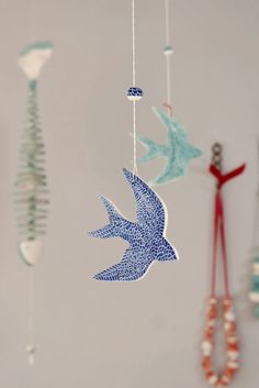 some blue and white birds hanging from strings on the wall next to other items that include beads