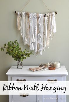 a white dresser with ribbons hanging from it's sides and the words ribbon wall hanging above