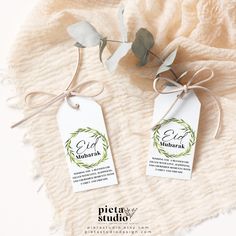 two tags are tied to the side of a white blanket with a green leaf on it