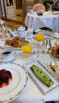 the table is set for breakfast with fruit and juice on it, along with other food items