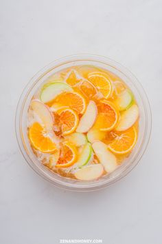 a bowl filled with oranges and cucumbers on top of a white table