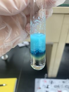 a hand holding a test tube filled with blue liquid and flecky white substance