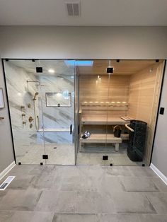 a bathroom with a walk in shower next to a wooden bench and tiled flooring