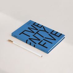 a blue book sitting on top of a white table next to a pen and pencil