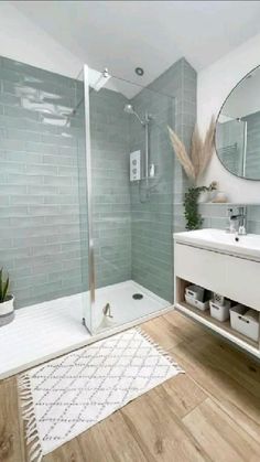 a bathroom with a sink, mirror and shower in it's corner area next to a rug on the floor