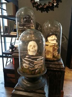 there are two glass domes with skulls in them on top of each other, one has a book and the other is a skull