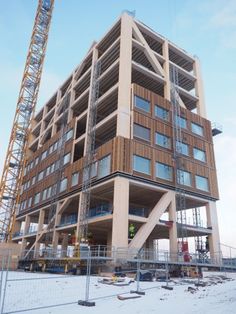 a tall wooden building sitting on top of a snow covered ground next to a crane